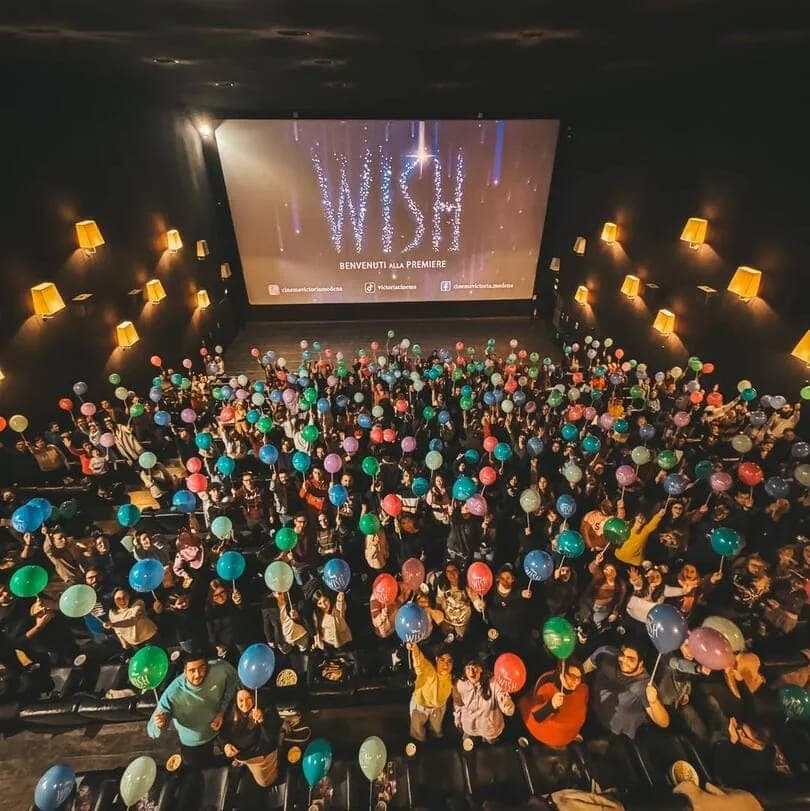 Una sala del cinema piena di pubblico con palloncini colorati